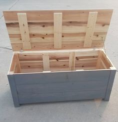 an open wooden box sitting on top of a cement floor next to a sidewalk with no one around it