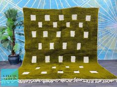 a green rug with white squares on it and a potted plant next to it