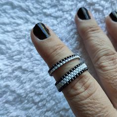 a woman's hand with black and white nail polish holding two rings on her finger