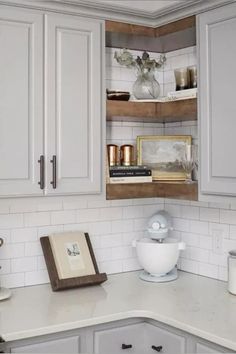 a kitchen with white cabinets and wooden shelves