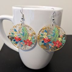 These delightful tropical earrings are made with lightweight circular resin pendants that are transparent with gold foil flecks, and nickel-free ear wires. Dangle length is approximately 1.5 inches, not including ear wires. To extend the life of your earrings, avoid contact with sweat, lotions, and other chemicals. Please message me with any questions. To see other jewelry options, check out my full store: https://www.etsy.com/shop/shopcraftyoctopus/ Summer Gold Resin Earrings, Gold Round Resin Flower Earrings, Round Flower Earrings As A Summer Gift, Gold Round Flower Earrings In Resin, Round Resin Flower Earrings, Multicolor Round Resin Earrings, Flower Transparent, Tropical Earrings, Resin Pendants