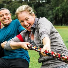 a group of people playing tugo ball in a field with one woman holding the rope