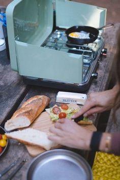 a person cutting up food on top of a wooden table next to a toaster oven