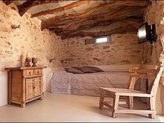 a bedroom with stone walls and exposed ceiling