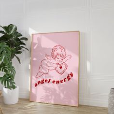 a pink poster with an angel on it next to a potted plant