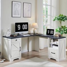 a corner desk with two computer monitors and a plant in the corner next to it