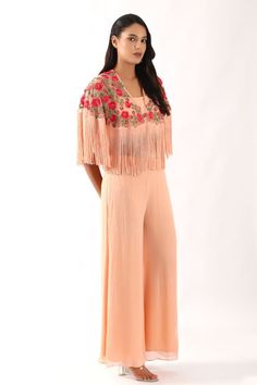 Peach cape crafted in net with all over multithread gul bahar embroidery and fringed hem detailing. Paired with a plain georgette blouse and flared pant. - Aza Fashions Traditional Spring Sets With Tassels, Traditional Tassel Sets For Spring, Fitted Tassel Sets For Spring, Fitted Sets With Tassels For Spring, Fitted Spring Sets With Tassels, Spring Bohemian Sets With Tassels, Spring Party Embroidered Palazzo Set, Spring Festive Sets With Tassels, Festive Spring Sets With Tassels