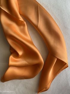 Luxurious natural mulberry silk square scarf, color orange, size: 65 cm x 65 cm / 26 in x 26 in. Soft, smooth, and lustrous silk charmeuse fabric, breathable and skin-friendly feels very soft and comfortable to wear. Can style in many ways: you can wear this scarf as a soft neck scarf, as a hair tie, as a headband scarf, as a wrist scarf, as a purse accessory. Or style it in any way you want with your own sense of creativity! Suitable for all seasons and is a great gift idea for special occasions. Care Instructions: Pure silk is a type of organic, natural and delicate fabric, please avoid washing. Dry clean recommended. Stored in a cool, dry, and dark place. To smooth out wrinkles and creases naturally, you may hang the scarf for a while as it will straighten out on its own. Ironing revers Silk Scarves Perfect For Gifts, Satin Silk Scarf Gift, Solid Silk Scarf Gift, Elegant Orange Silk Scarf For Gift, Elegant Orange Silk Scarf As Gift, Elegant Orange Silk Scarf, Silk Orange Scarves As A Gift, Orange Silk Scarves As A Gift, Silk Orange Scarves As Gift