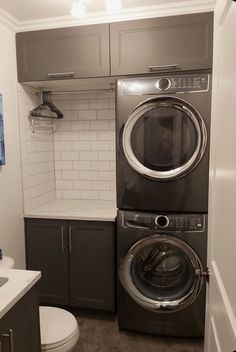 a washer and dryer in a small room with white tile on the walls