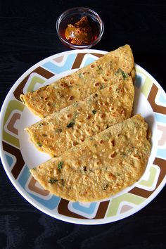 three flat breads on a plate with dipping sauce