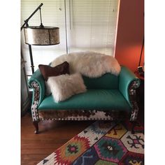 a green chair with two pillows on it in front of a lamp and a rug