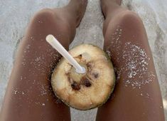 a person is standing in the sand with an apple slice and a white plastic straw