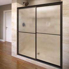 a bathroom with a glass shower door and wood flooring on the side of the room