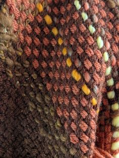 an orange and brown knitted blanket sitting on top of a table