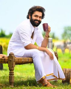 a man sitting on a bench holding a cup