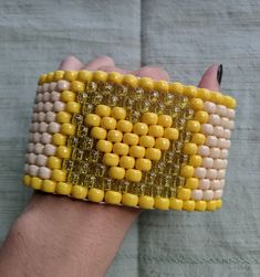 a hand holding a yellow and white beaded bracelet with two rows of beads on it