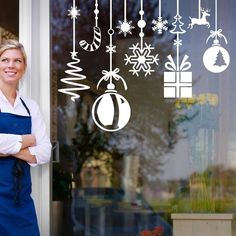 a woman standing in front of a glass door with christmas decorations hanging from the window