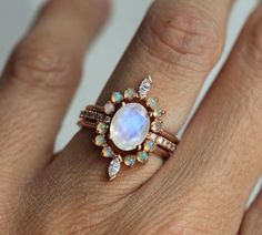 a woman's hand wearing a ring with an opal and diamonds on it