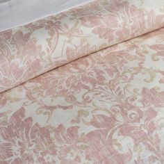 a bed with a pink and white comforter next to a pillow on top of it