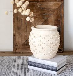 a white vase sitting on top of a stack of books