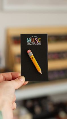 a person holding a yellow pen in their left hand and a black card with the word miss written on it