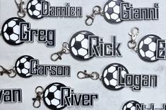 several key chains with soccer balls and name tags attached to them, all in black and white