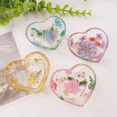 three heart shaped glass dishes sitting on top of a white table next to a plant