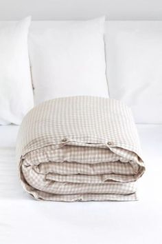 an unmade bed with white sheets and pillows