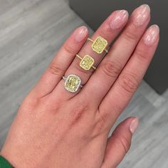 a woman's hand with three different rings on her left and one yellow ring on the right