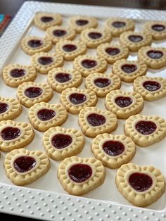 small cookies with jam in the middle on a white platter, ready to be eaten