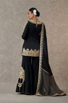 Step into sophistication with this short kurta adorned with haath-phool and kamal motifs in dori, sitara, and dabka kaam. The full sleeves are elegantly edged with kinari, and it features a zero neckline with a center back closure and side zip. The matching sharara is adorned with shajara motif, dabka work, and kinari edging, secured with a side zip closure. Complete the ensemble with a digital printed patchwork organza dupatta, embellished with an embroidered border and edged with kinari, addin Sharara Heavy, Haath Phool, Kurta And Sharara, Dabka Work, Caribbean Fashion, Black Kurta, Short Kurta, Lakme Fashion Week, Sharara Set