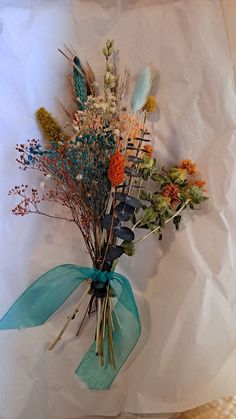 a bouquet of flowers sitting on top of a piece of white paper with blue ribbon