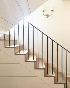 there is a stair case on the wall next to the stairs in this house with white walls and wood flooring