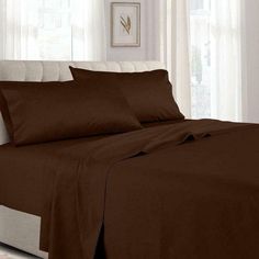 a bed with brown sheets and pillows in a room