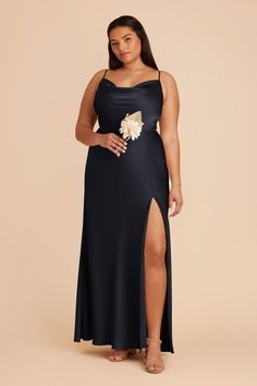 a woman in a black dress with a flower on the side and slited leg