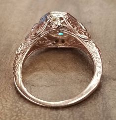 an antique style engagement ring is shown on a table with the center stone in the center