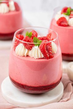 two desserts with strawberries and whipped cream in small dishes on a table top