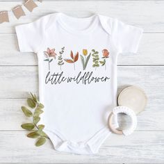 a baby bodysuit that says little wildflower with flowers and leaves on the front