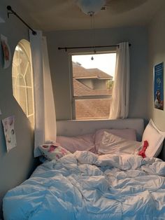 an unmade bed sitting in front of a window