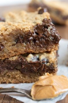 two chocolate chip cookie bars with peanut butter on top and one is cut in half