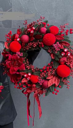 a man holding a wreath with red balls and greenery