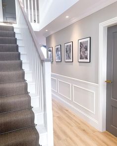 a staircase with pictures on the wall and carpeted stairs leading to another room in the house