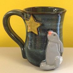 a ceramic mug with a penguin and star on the inside, sitting on a table