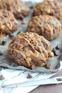 chocolate cookies with caramel drizzle and chocolate chips on a baking sheet, ready to be eaten