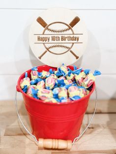 a red bucket filled with candy sitting on top of a wooden table