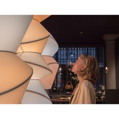 a woman standing next to a large lamp in a room with lots of lights on it