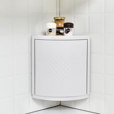 a white cabinet sitting on top of a tiled wall