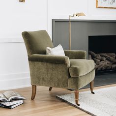 a green chair sitting in front of a fire place with a book on the floor