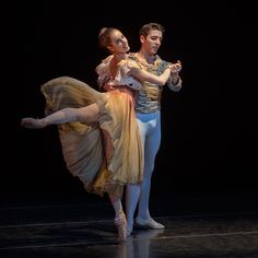 two ballerinas are performing on stage with one holding the other's leg