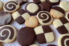 some cookies that are sitting on a white table cloth with brown and white icing